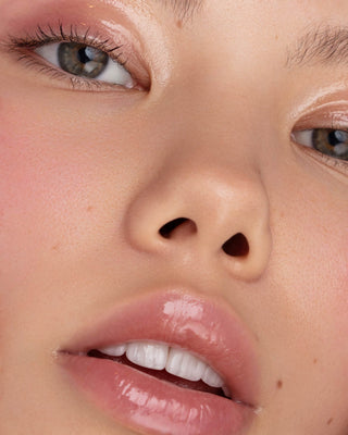 Close-up of model with light-medium skin wearing EM Cosmetics Morning Dew Lip Gloss for a juicy, glassy lip look.