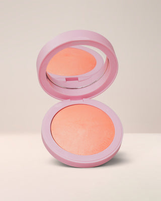 Open compact of EM Cosmetics Heaven's Glow Radiant Veil Blush in Elysium, a bright peach-coral shade, showing the marbled, satin powder texture.