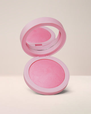 Open compact of EM Cosmetics Heaven's Glow Radiant Veil Blush in Seraph, a soft pink shade, showing the marbled, satin powder texture.