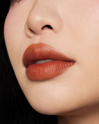Michelle Phan wearing EM Cosmetics Phantom Blur Lip Tint in Sienna, creating a soft, warm burnt orange blurred lip.